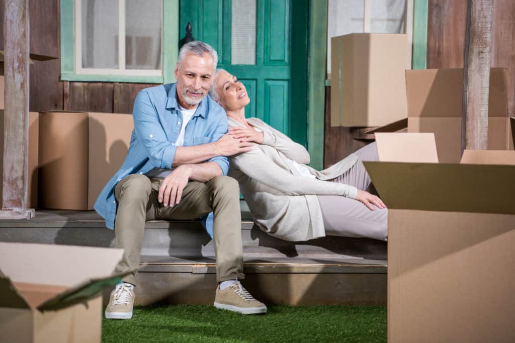 Senior couple sitting on the floor between moving boxes
